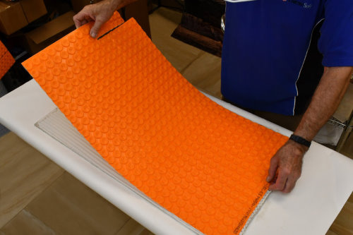 Floor heating with ThermoTile cable on Schluter membrane installation step 3 - Spread thinset on subfloor and install membrane. Step 3 of installation of floor heating with ThermoTile cable on Schluter membrane is to spread thinset on subfloor and install. membrane.