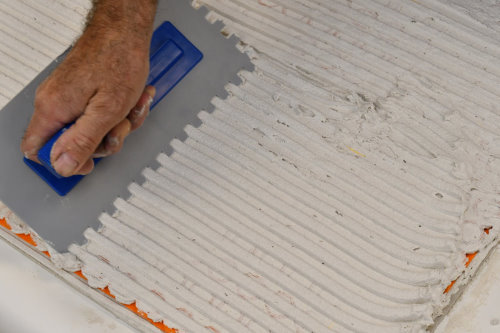 Floor heating with ThermoTile cable on Schluter membrane installation step 7 – Add appropriate amount of thinset and trowel notch-wise. Step 7 of installation of floor heating with ThermoTile cable on Schluter membrane is to add appropriate amount of thinset and trowel notch-wise.