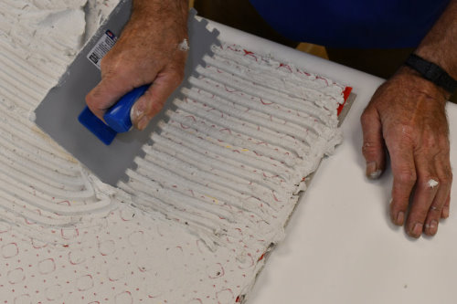 Floor heating with ThermoTile cable on PROVA membrane installation step 7 - Add appropriate amount of thinset and trowel notch-wise. Step 7 of installation of floor heating with ThermoTile cable on PROVA membrane is to add appropriate amount of thinset and trowel notch-wise.